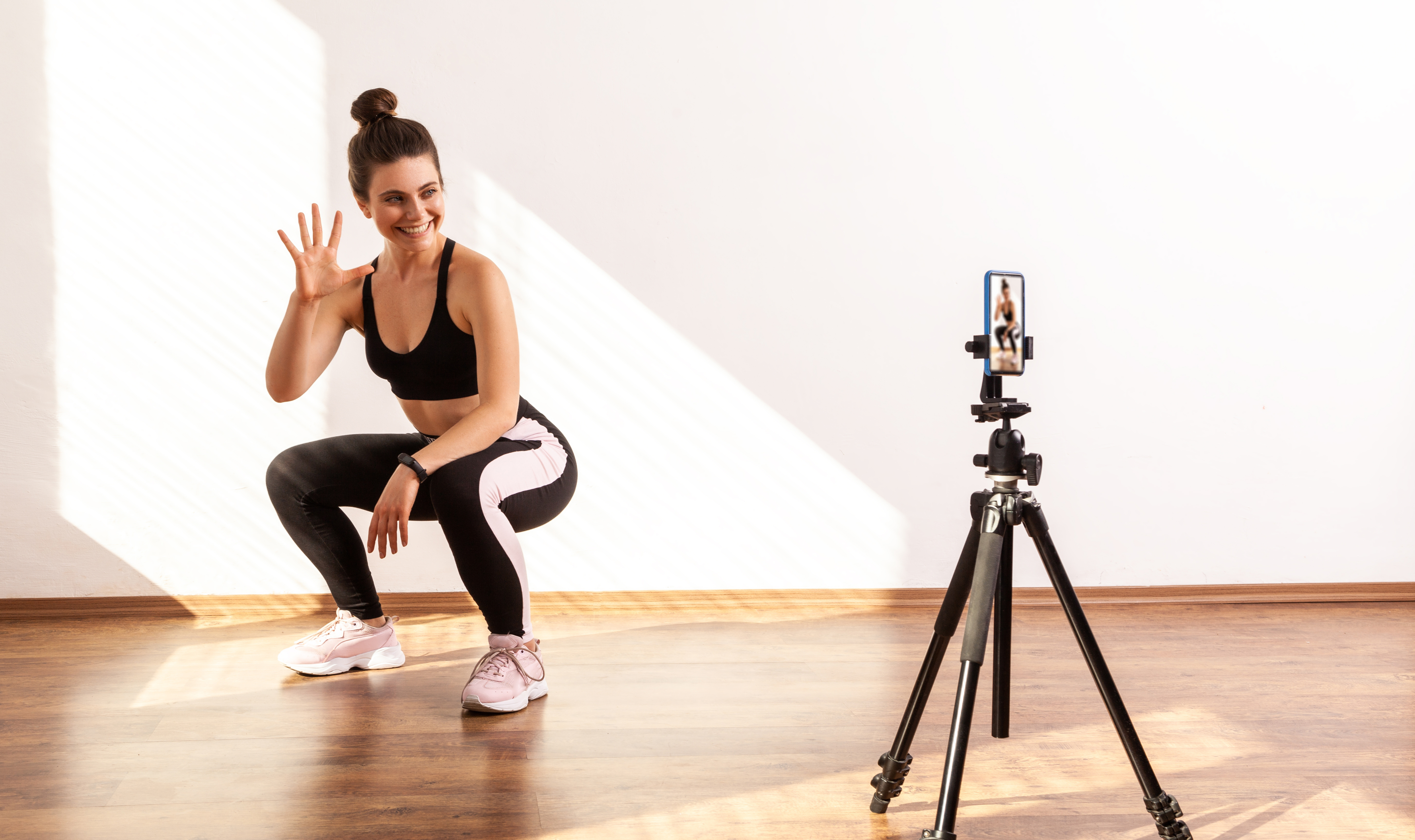 En kvinna som sitter på huk framför en kamera med ett stativ.