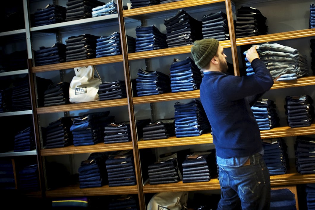 En man står framför hyllor med jeans.