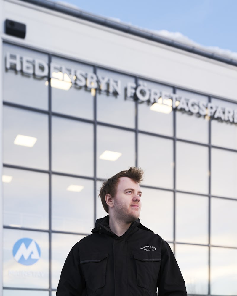 En man i en svart jacka som står framför en byggnad.