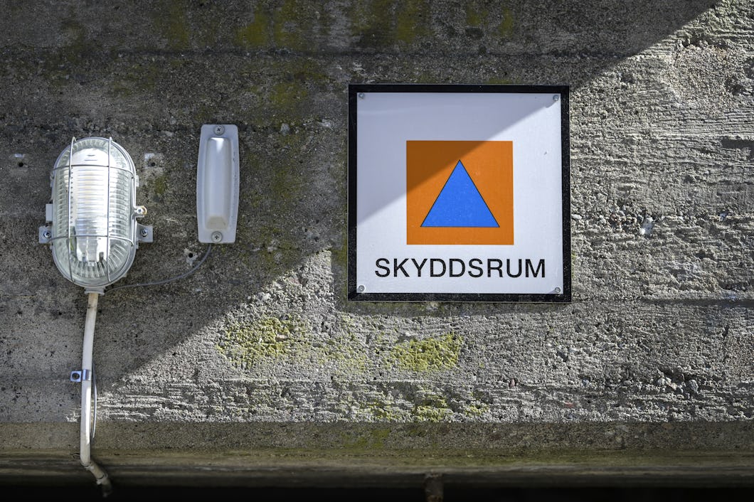 Skyddsrumsskylt på grå fasad.