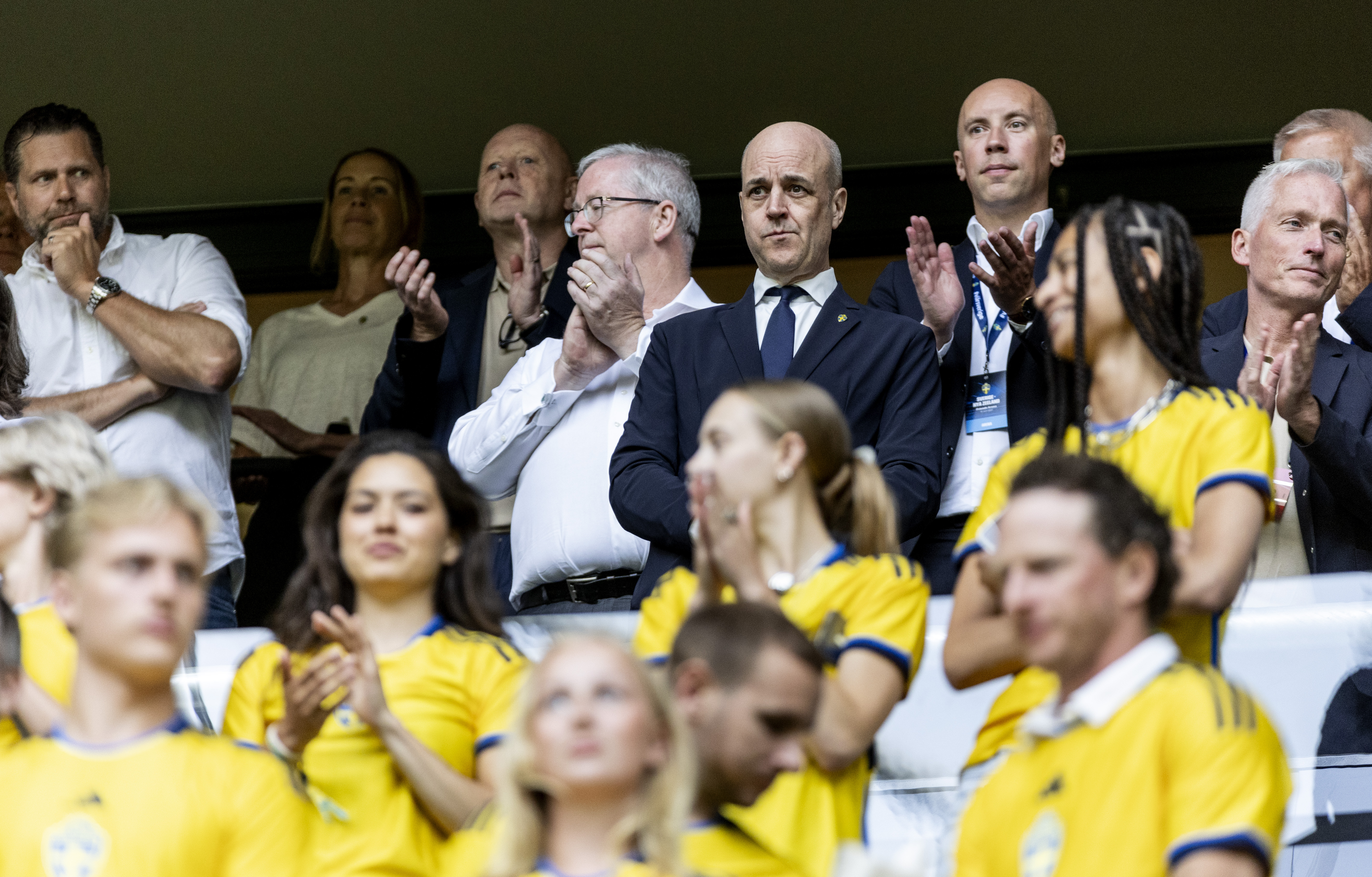 En grupp människor i sverige tröjor som klappar på en fotbollsmatch.