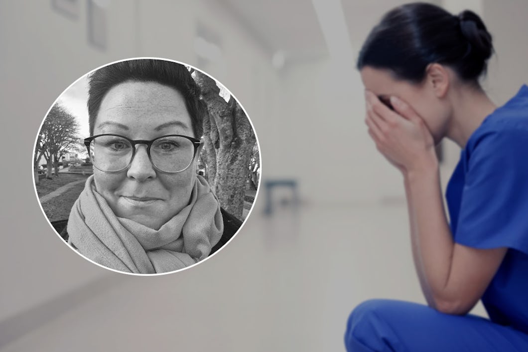 En ledsen sjuksköterska sitter på golvet och håller händerna föransiktet