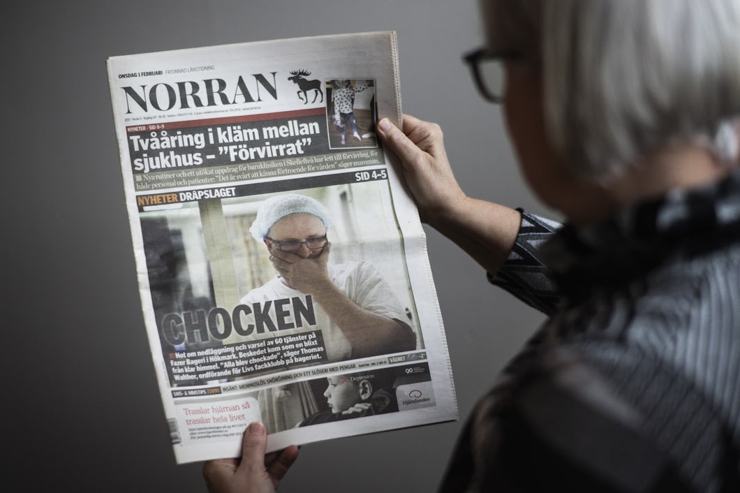Person som läser en tidning om beslutet om varsel