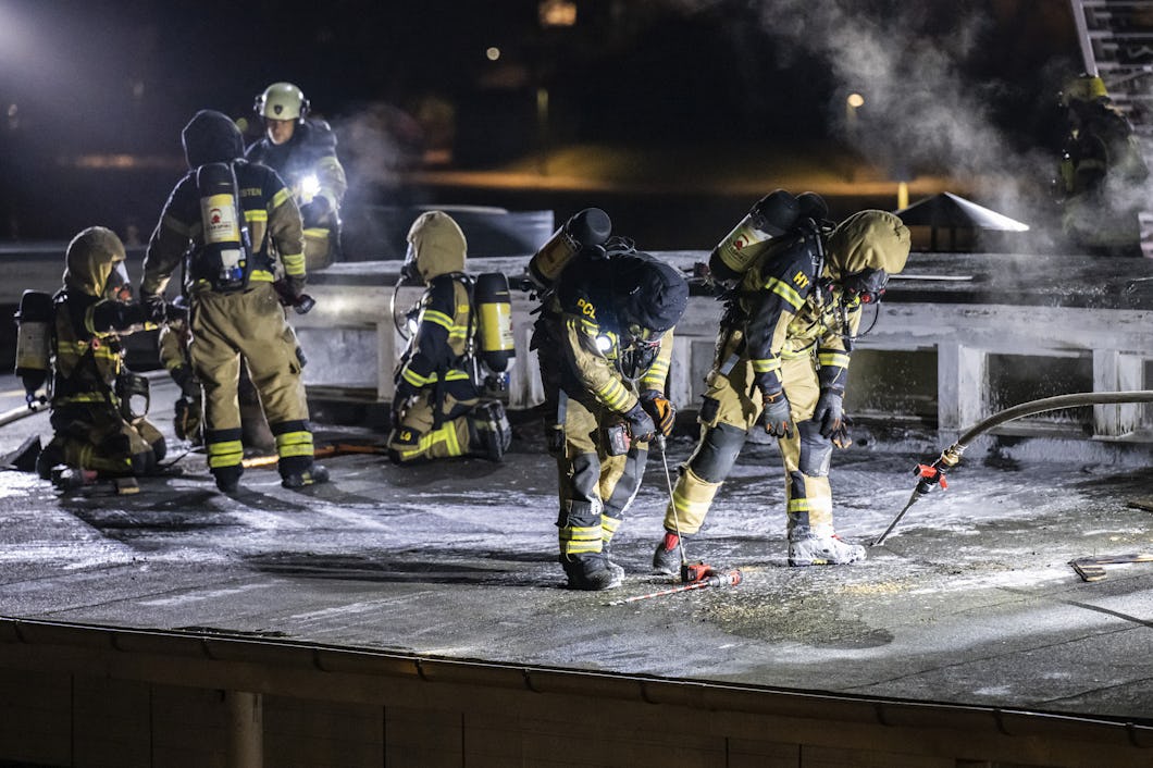 En grupp brandmän som arbetar på ett tak på natten.