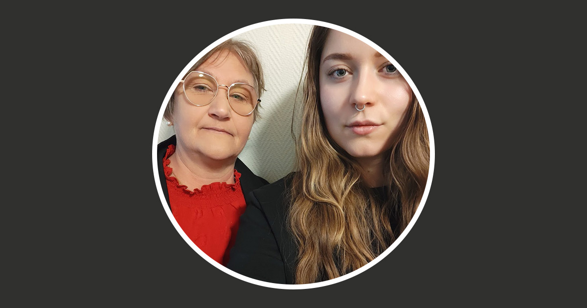 Två kvinnor som poserar för ett foto, en med glasögon och en röd topp, den andra med näsring och långt hår.