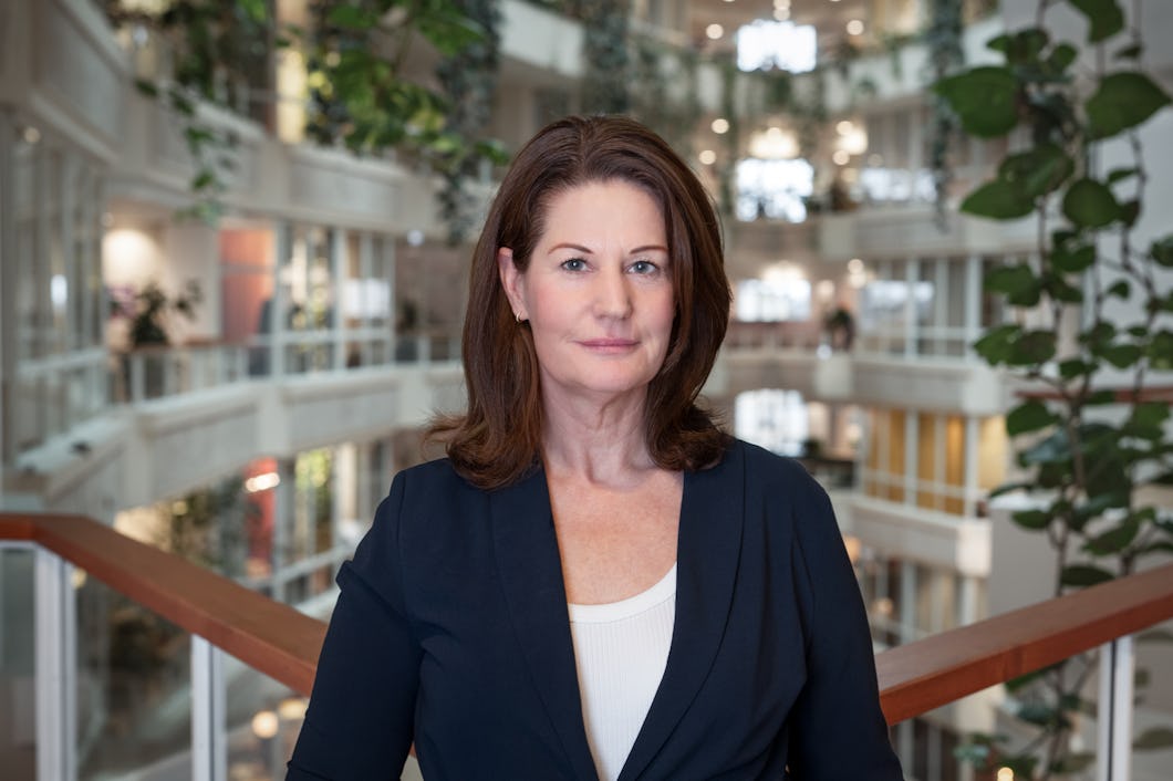 Jeanette Hedberg står i en stor foajé med växter och trappor.