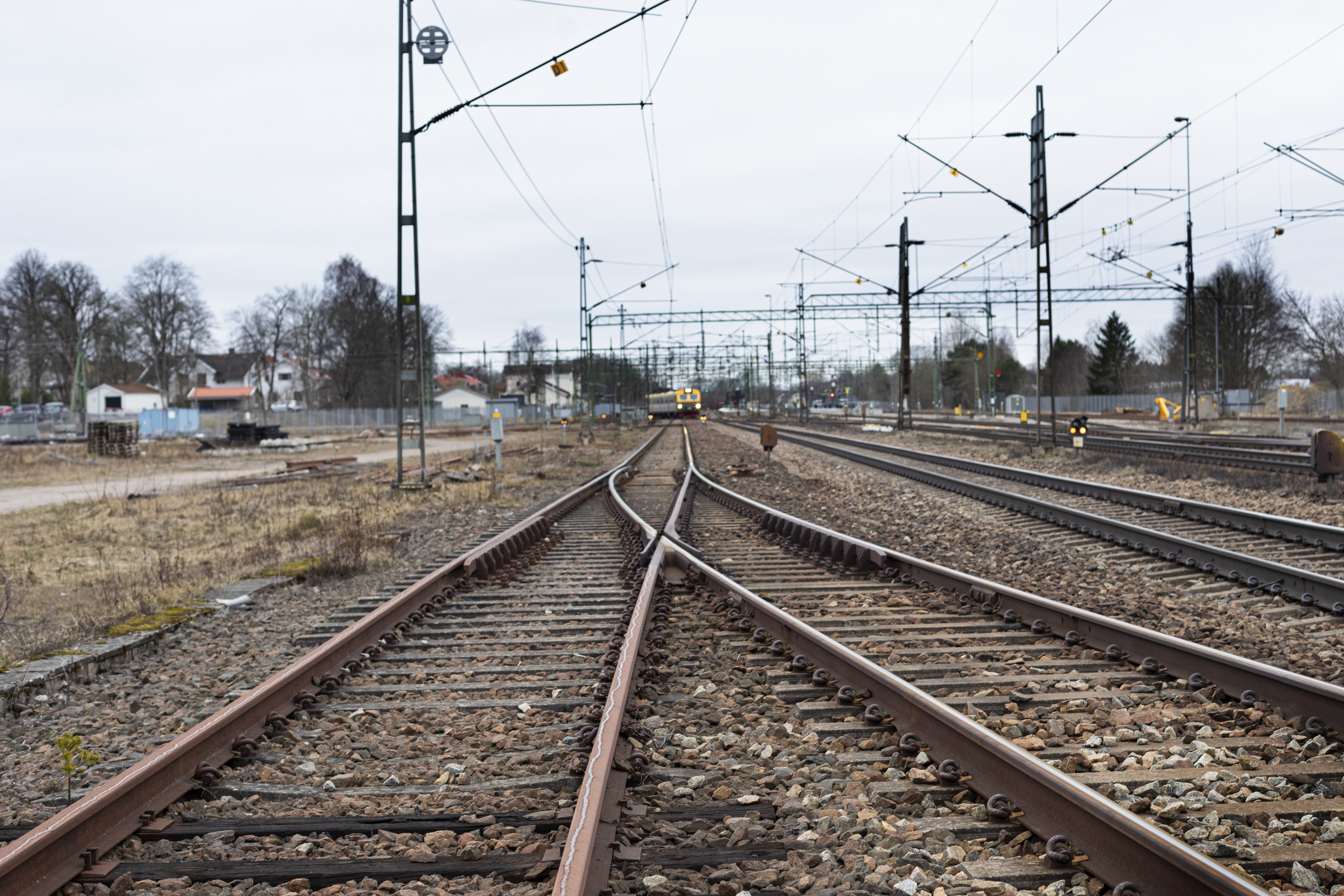 Järnvägsspår med ett lokaltåg i bakgrunden.