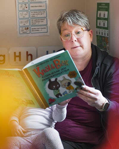 Barnskötare Cristine Jonasson som läser en bok för ett barn i ett rum.