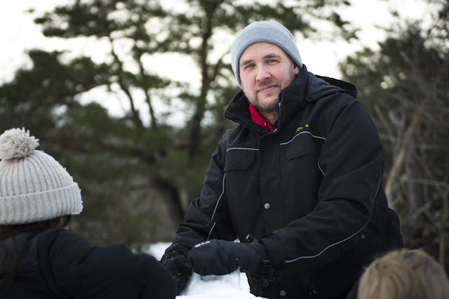 Barnskötare Henrik Karlsson i en svart jacka leker i snö med några förskolebarn