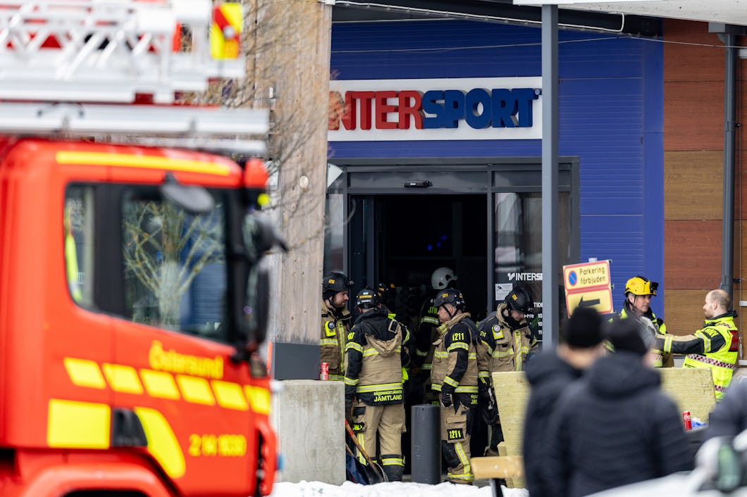 En brandman framför en butik med en brandbil i bakgrunden.