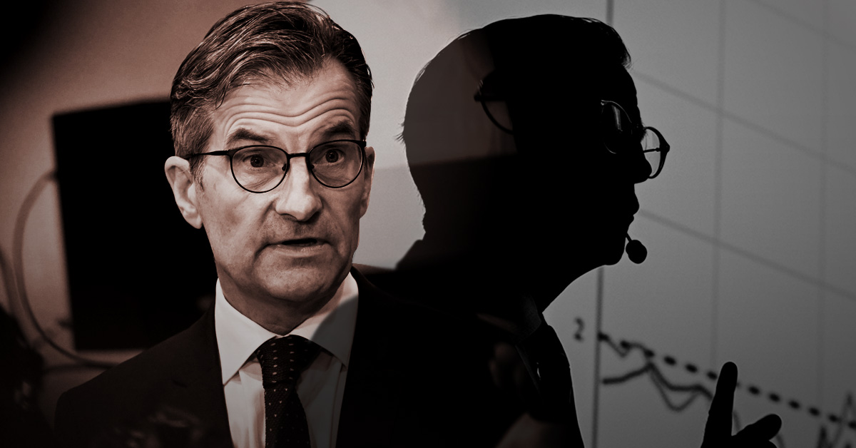 En man i kostym ger en presentation med sin skugga reflekterad på en skärm som visar grafer.