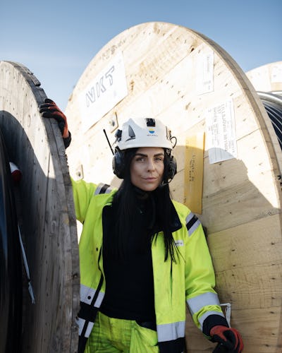 Angelica Jonsson står mellan två stora rullar med kabel.