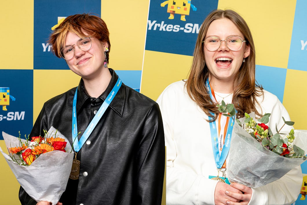 Två kvinnor håller buketter och bär medaljer.