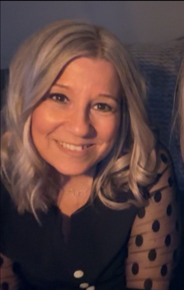 Gittel Larsson med blont hår i ett svagt upplyst rum.