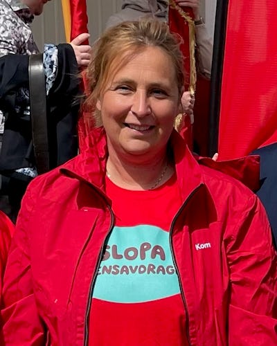 Kvinna i en röd jacka och t-shirt ler mot kameran.