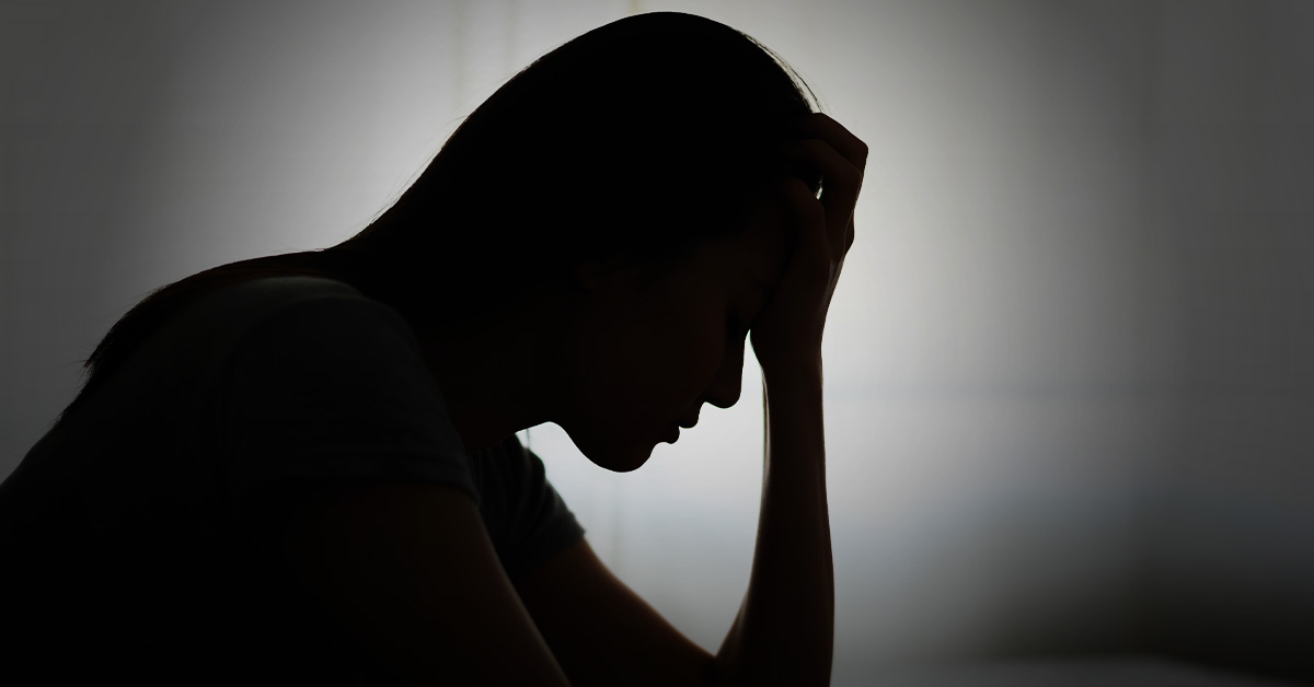Siluett av en person som håller huvudet i en gest av nöd eller sorg.