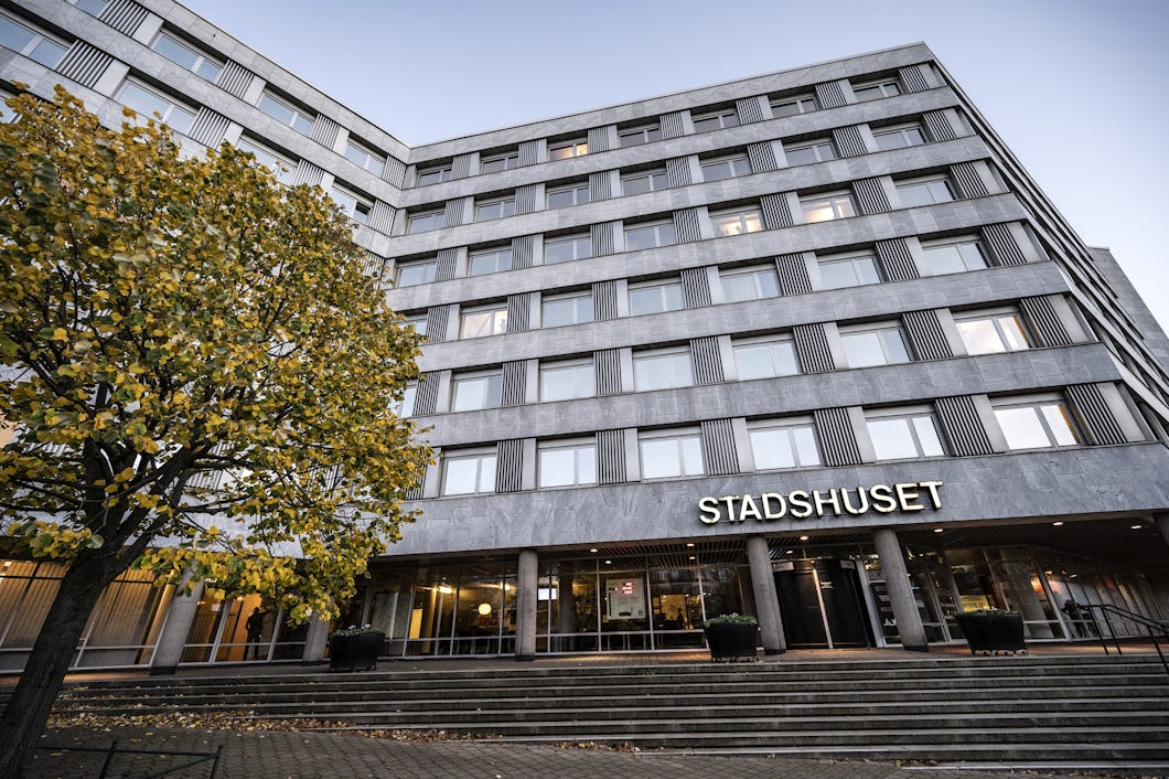 Modernt kommunhus med "stadshuset" skylt och höstträd.