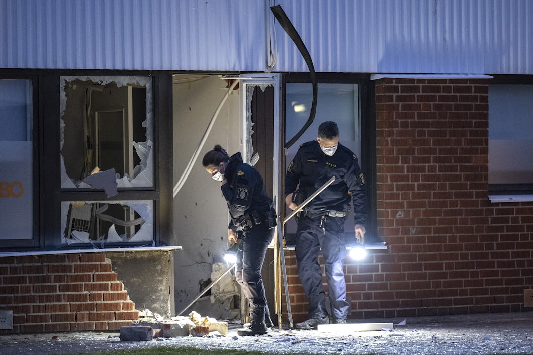 Bild på två poliser som undersöker ett krossat fönster på en tegelbyggnad.