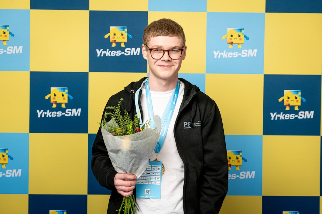 Person står med medalj och blommor.