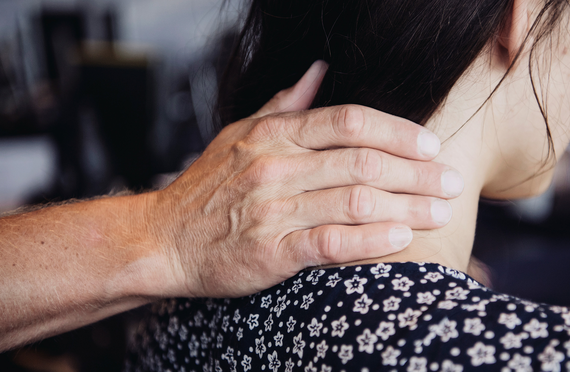 En person med en blommig skjorta har handen placerats på nacken.