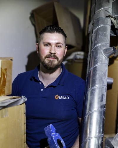 Porträtt på Johan Söderberg som står bland kartonger med en slägga i händerna.