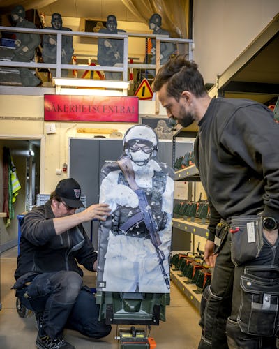Kent Persson och Andreas Grimmesten preparerar en måltavla med en bild på en soldat.