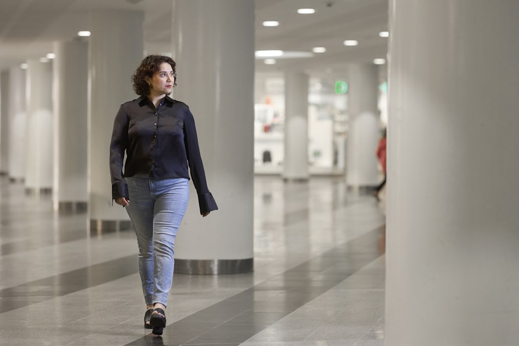 En person går genom en rymlig hall upplyst av belysning och omgiven av vita kolonner.
