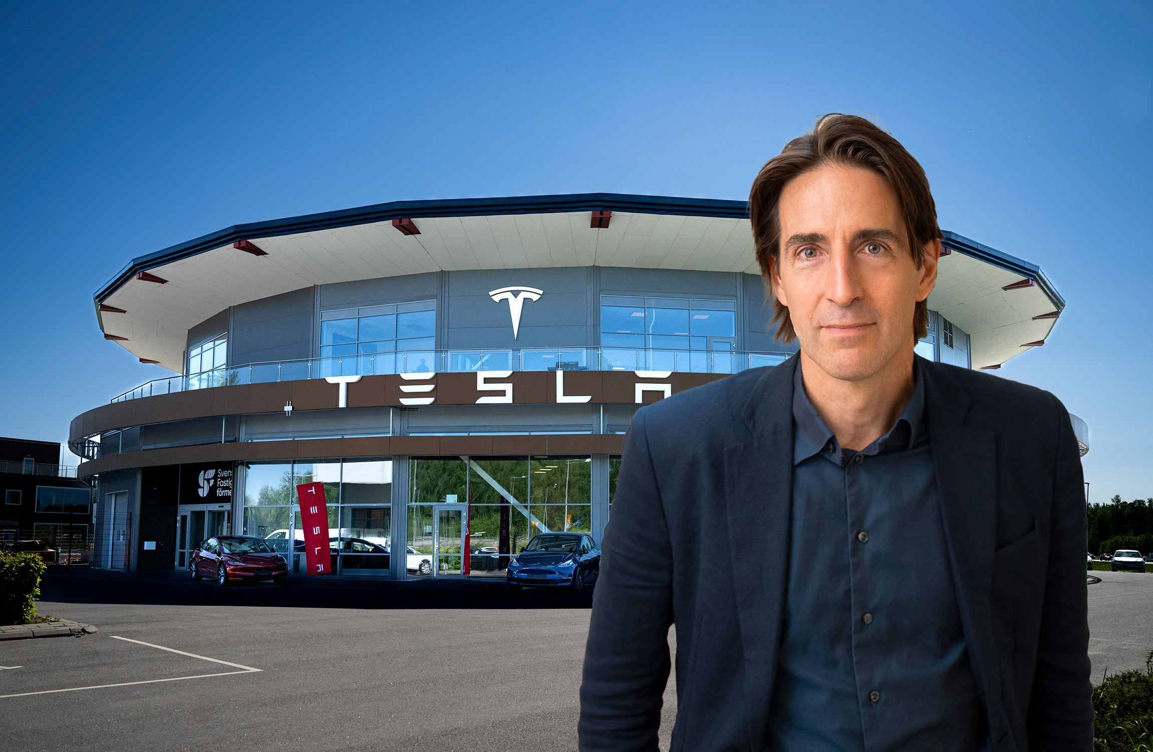 En man i kostym står framför en Tesla-återförsäljningsbyggnad.