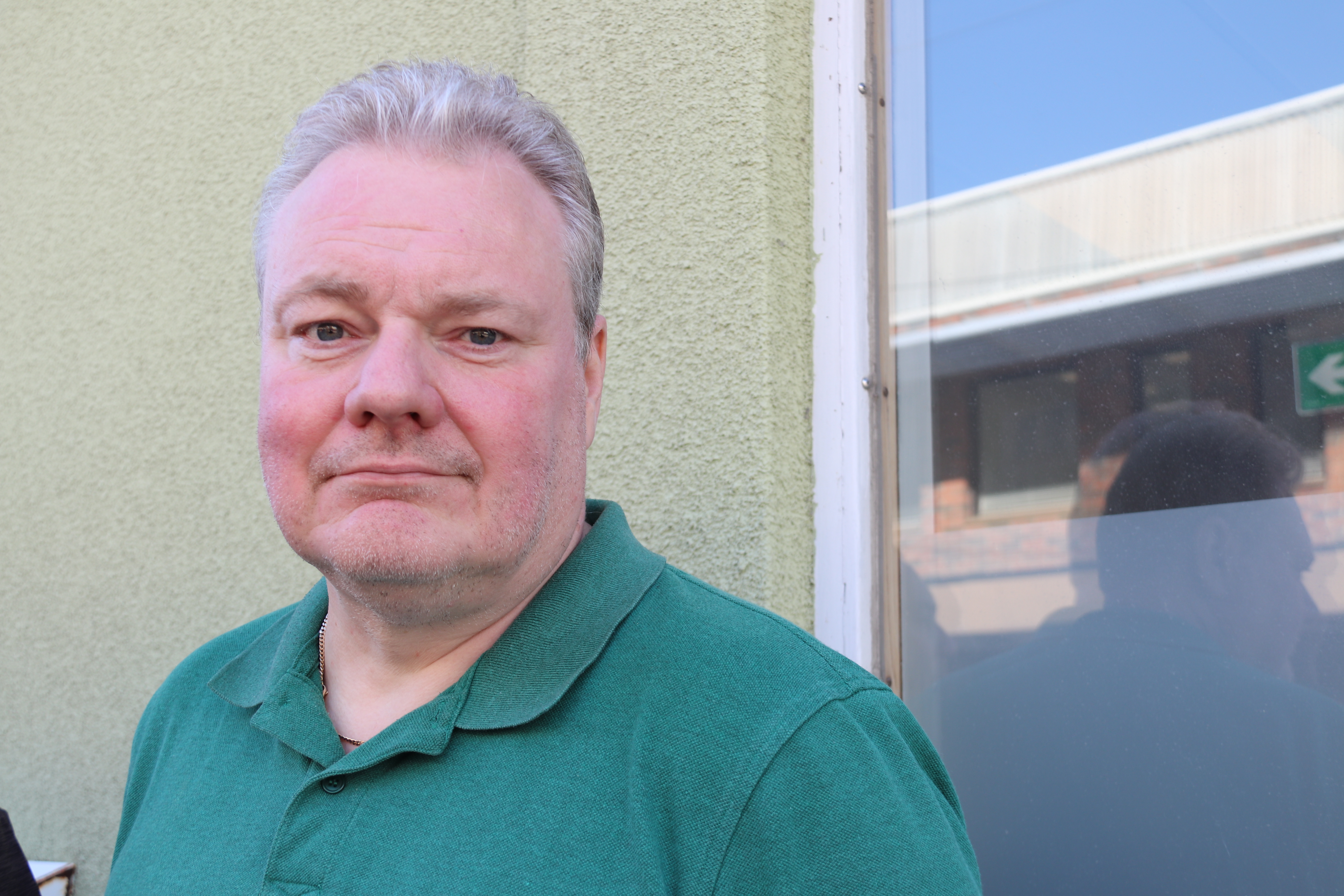 Man i grön tröja tittar i kameran.