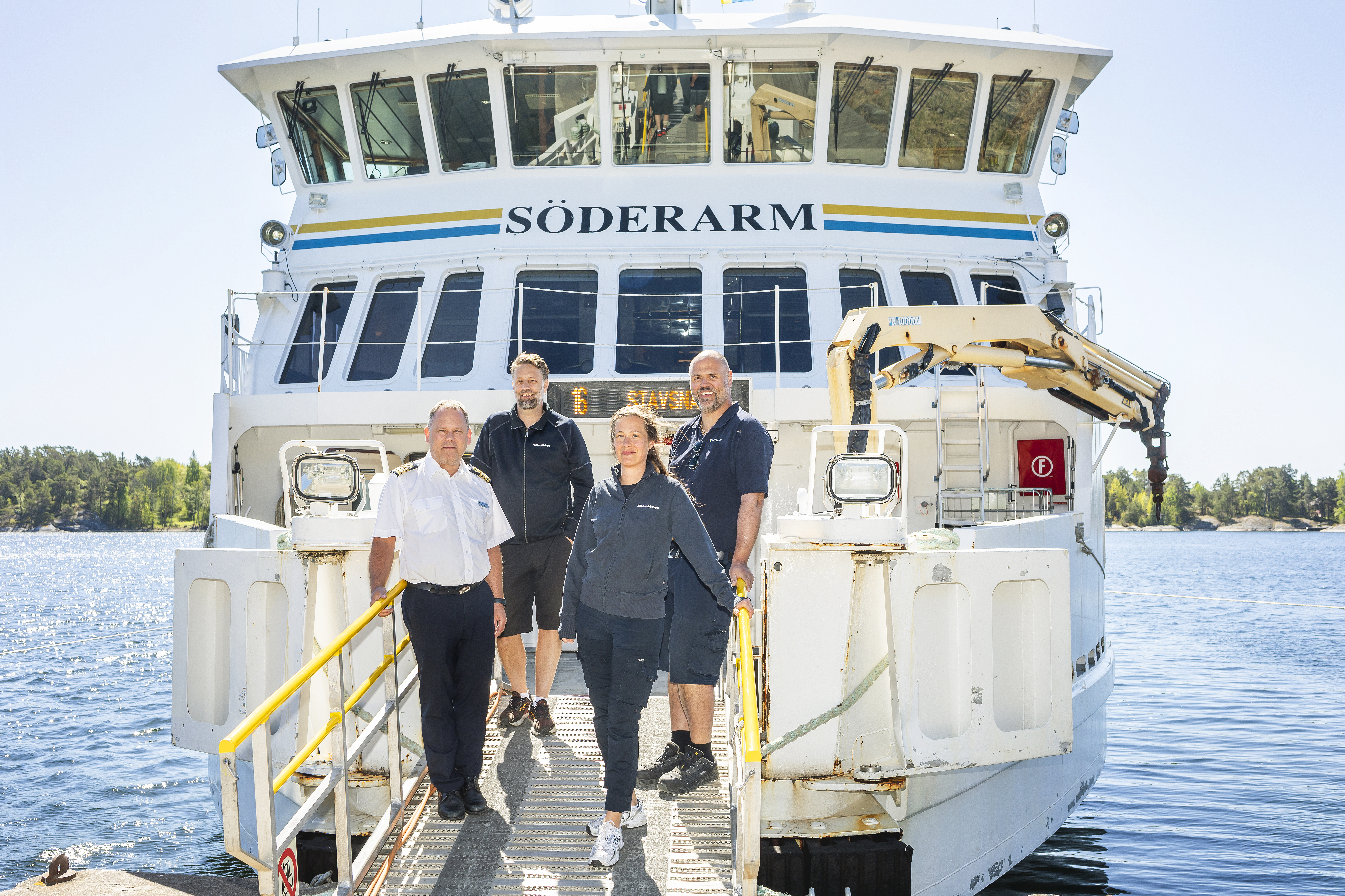 Medarbetare poserar framför skärgårdsbåten de jobbar på.