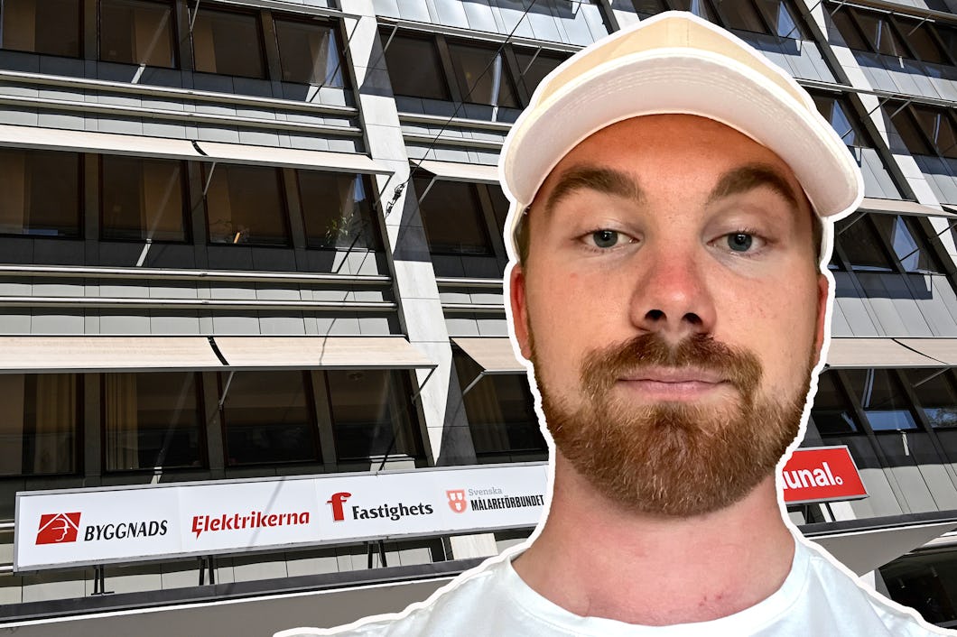 En man i vit keps står framför en byggnad med stora fönster och en vit skylt som visar olika organisationers logotyper och namn.