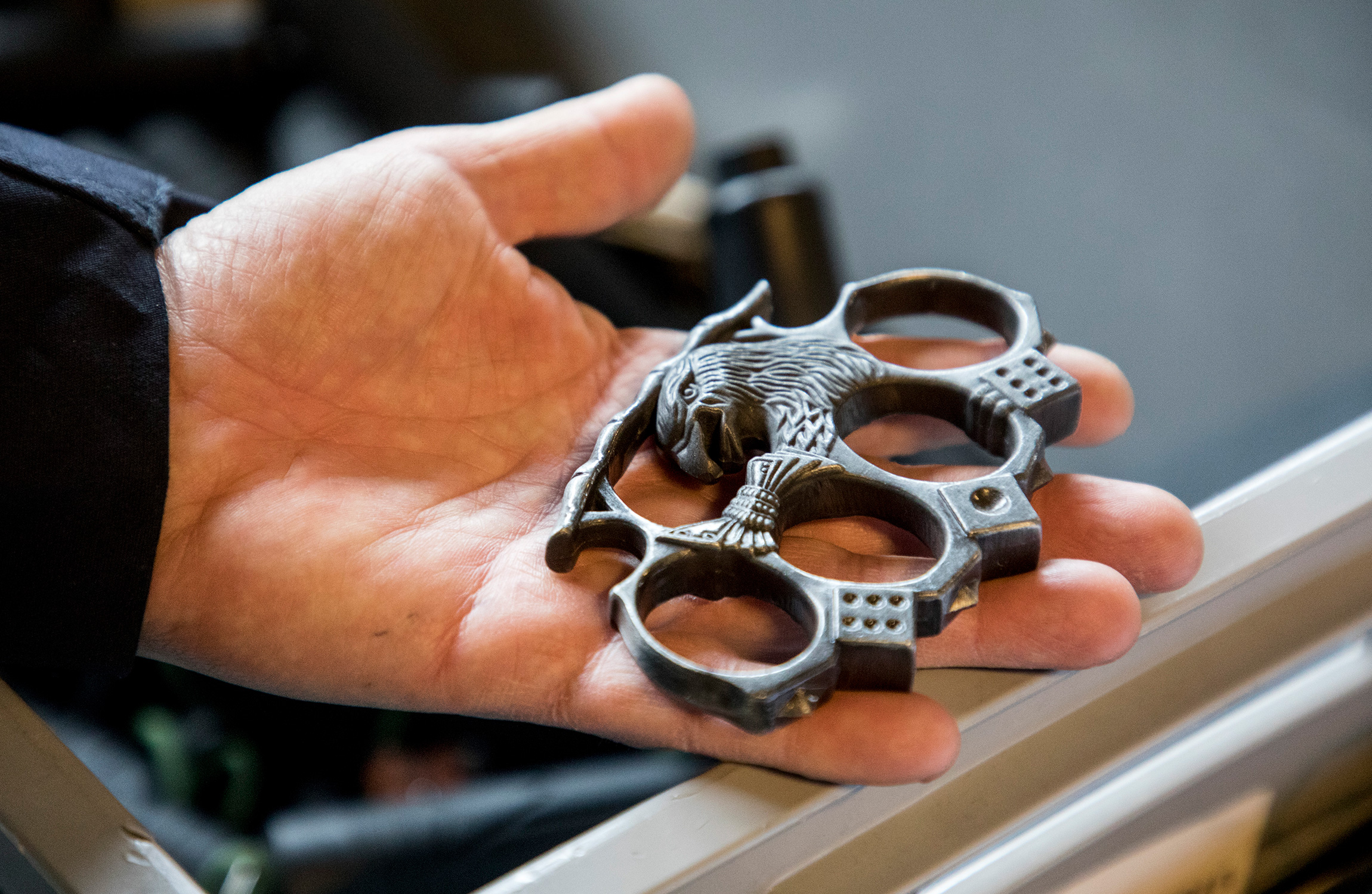 En person håller ett par knogjärn med en utsmyckad örndesign.