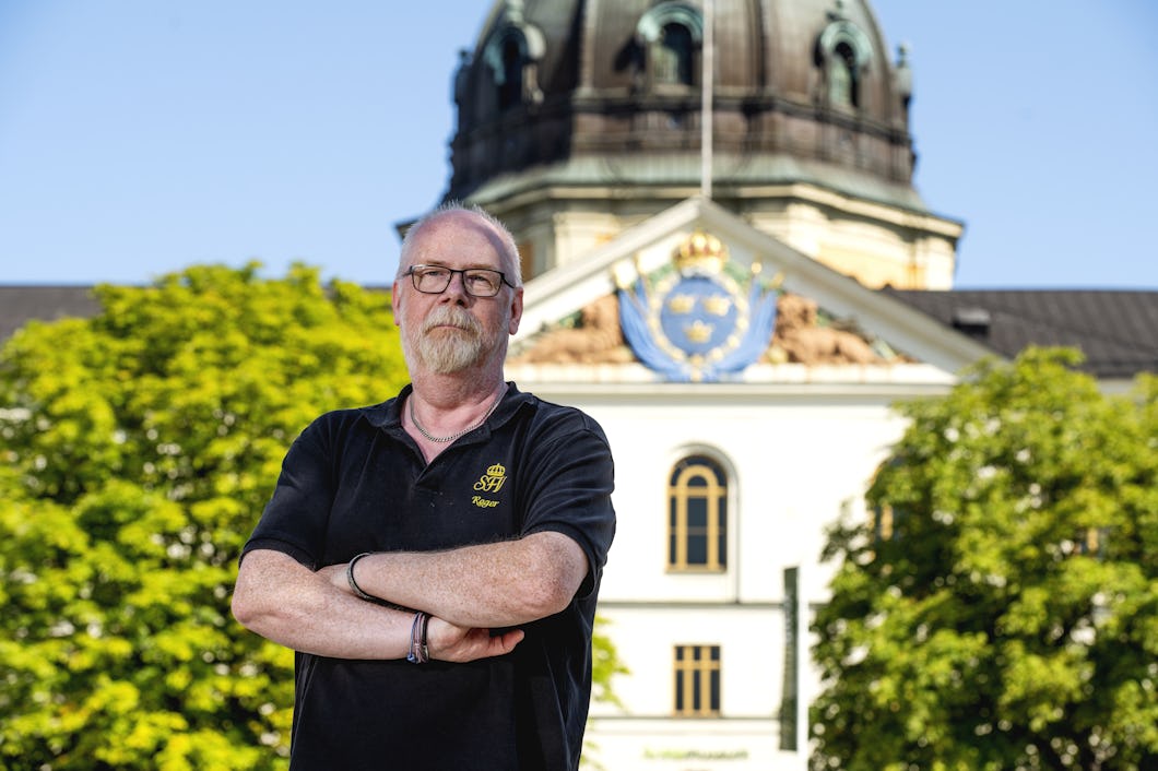 Roger Carlsson står med armarna i kors framför en Armémuseums byggnad med en kupol och ett utsmyckat emblem.