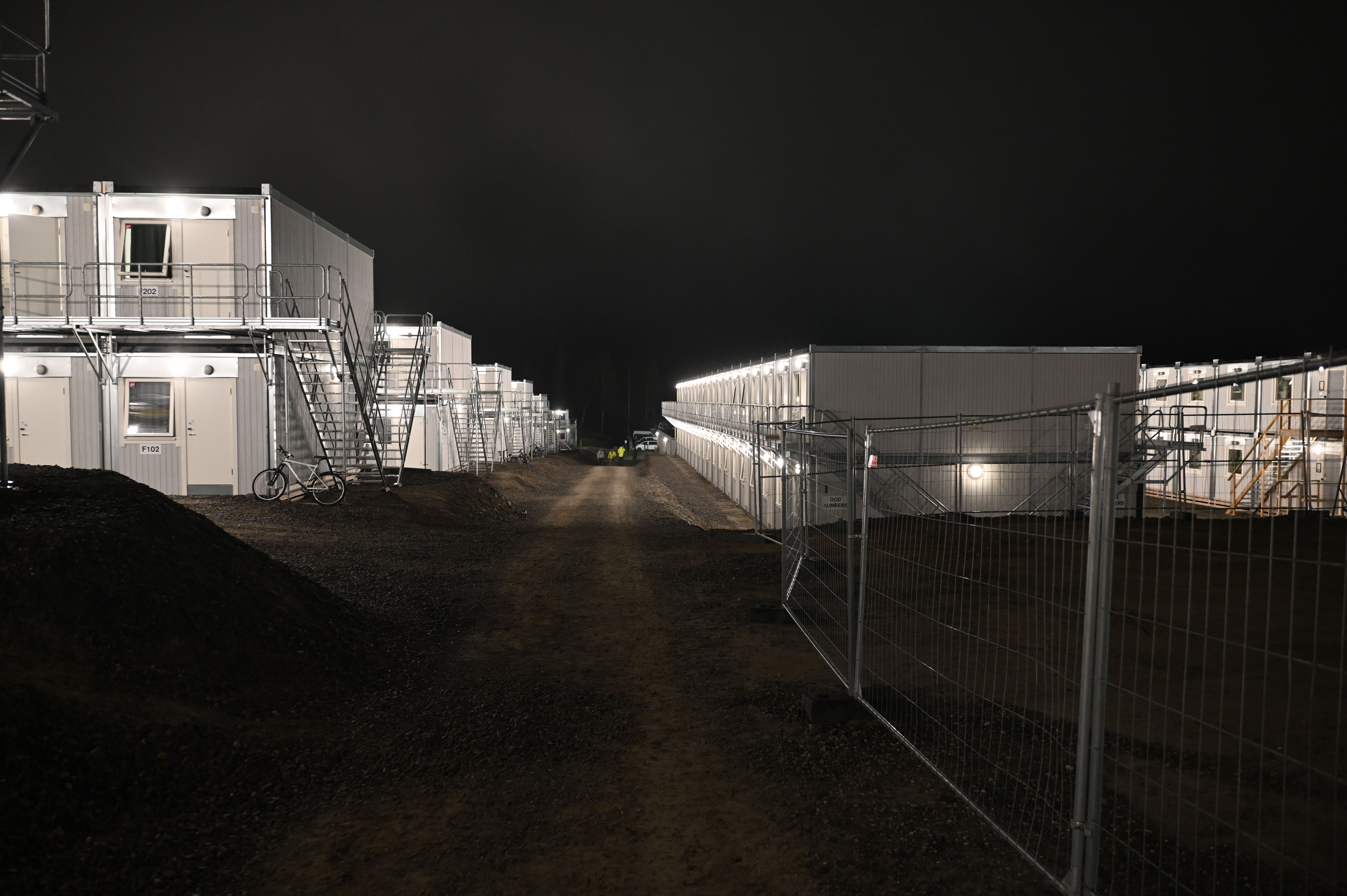Bild av en välbelyst, modern containerbostadskomplex på natten.