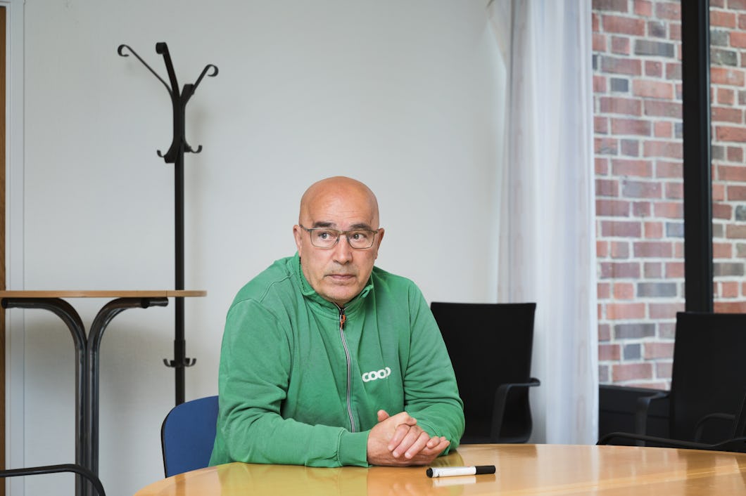 En man med glasögon och en grön huvtröja sitter vid ett konferensbord.