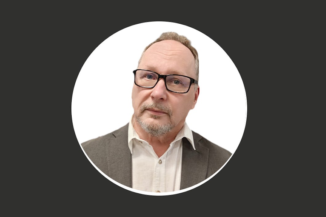 Kari Parman med glasögon och kavaj, neutral min, vit bakgrund, cirkulär ram.