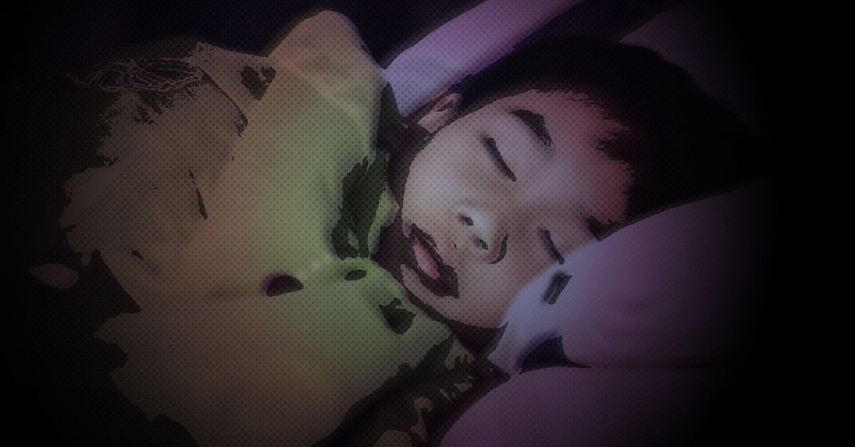 Ett barn som sover i en säng, täckt av en filt.