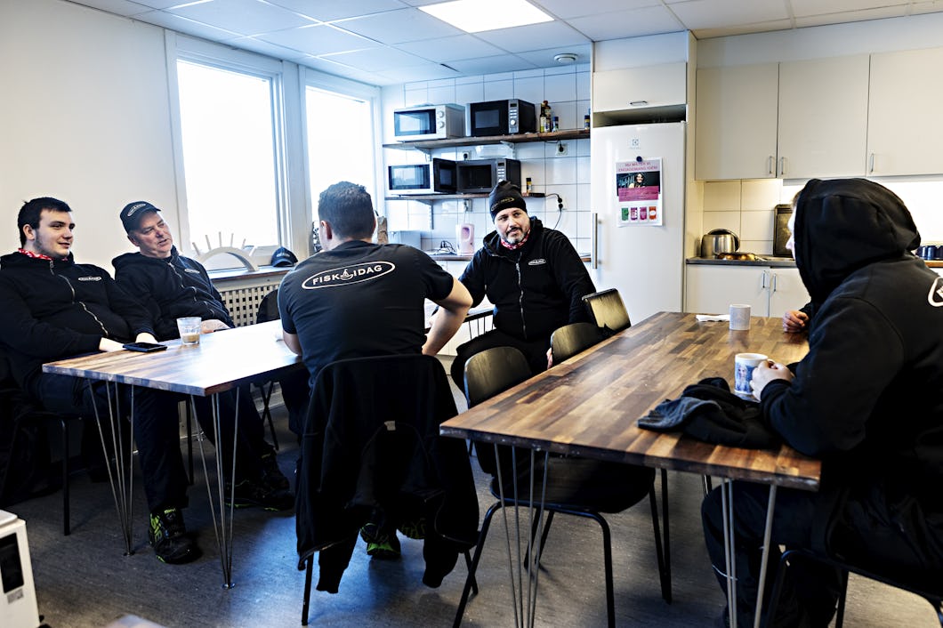 Andreas Långberg och kollegorna sitter runt bord i ett lunchrum. I bakgrunden syns en kyl, mikrovågsugnar och en vattenkokare.