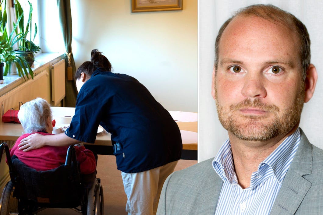 En vårdgivare hjälper en äldre person i rullstol vid ett bord. En man i kostym står bredvid dem.