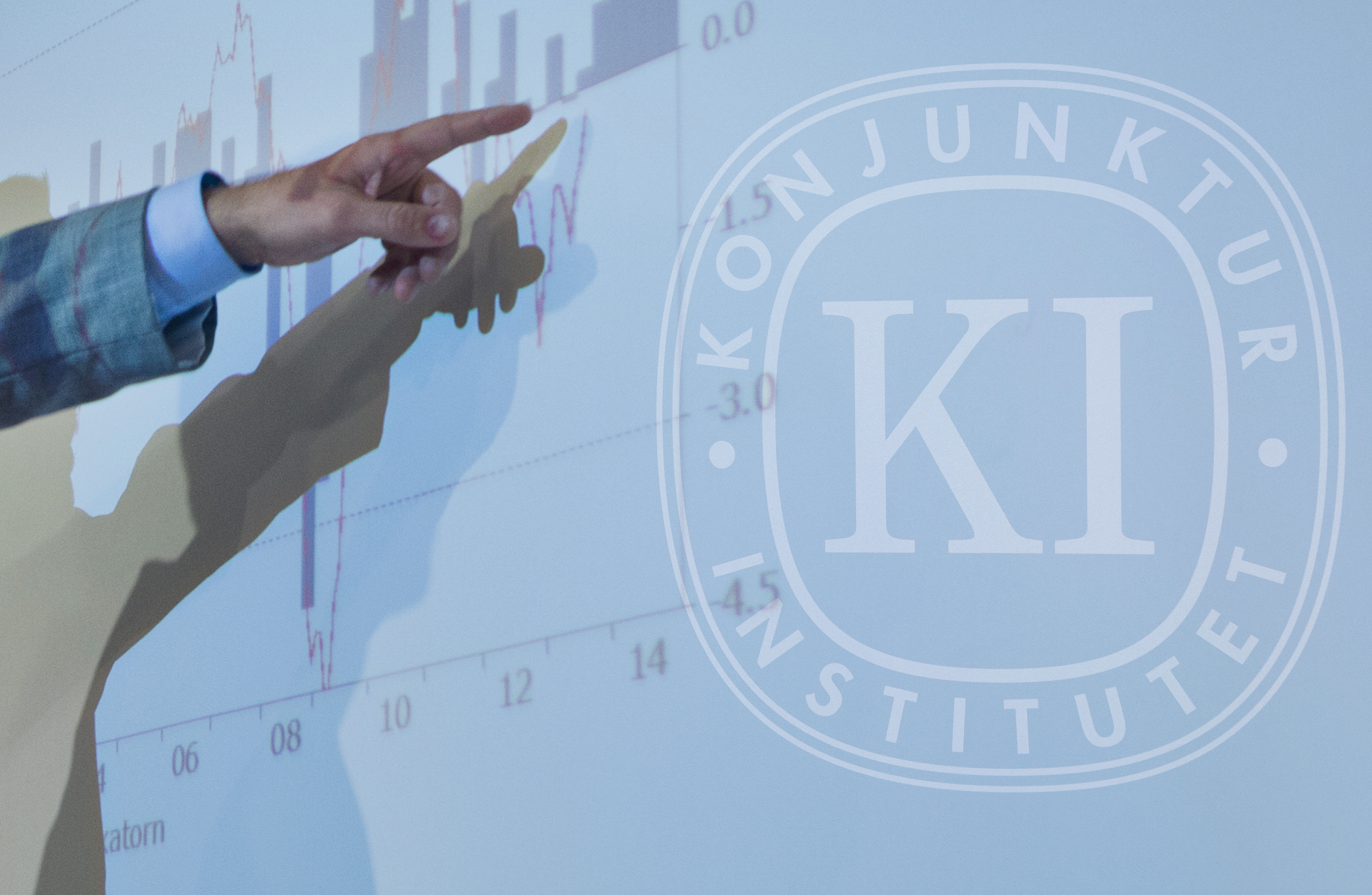 En person pekar på ett diagram som projiceras på en skärm. På skärmen syns även Konjunktur Institutets logotyp.