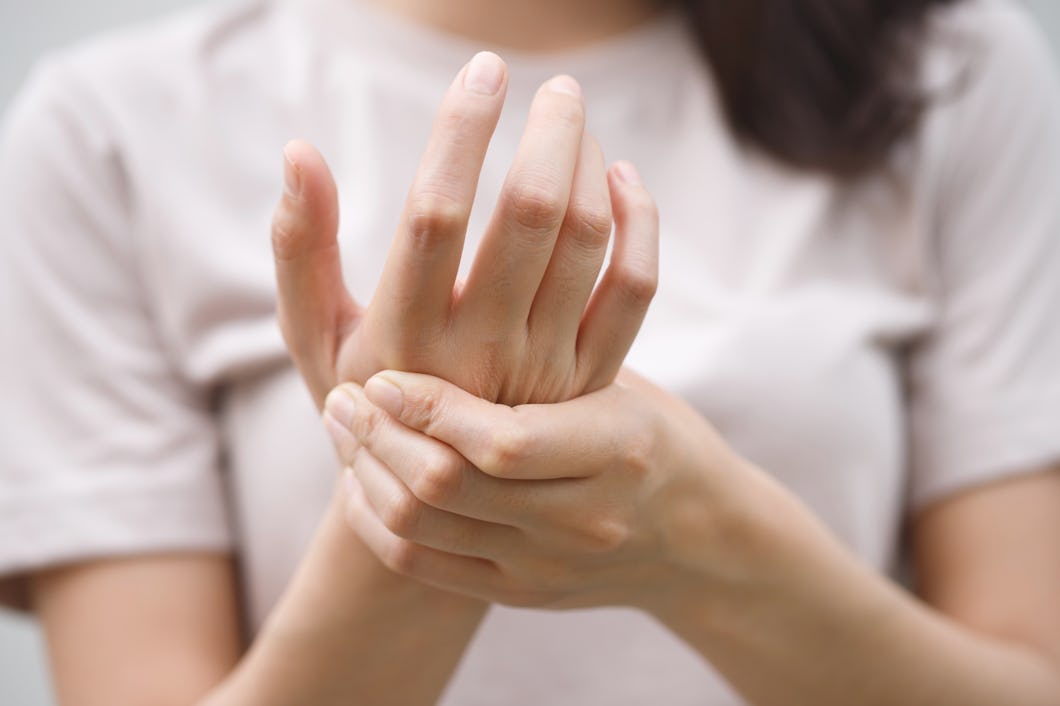 En person håller sin hand med den andra handen, vilket kan antyda smärta eller obehag.