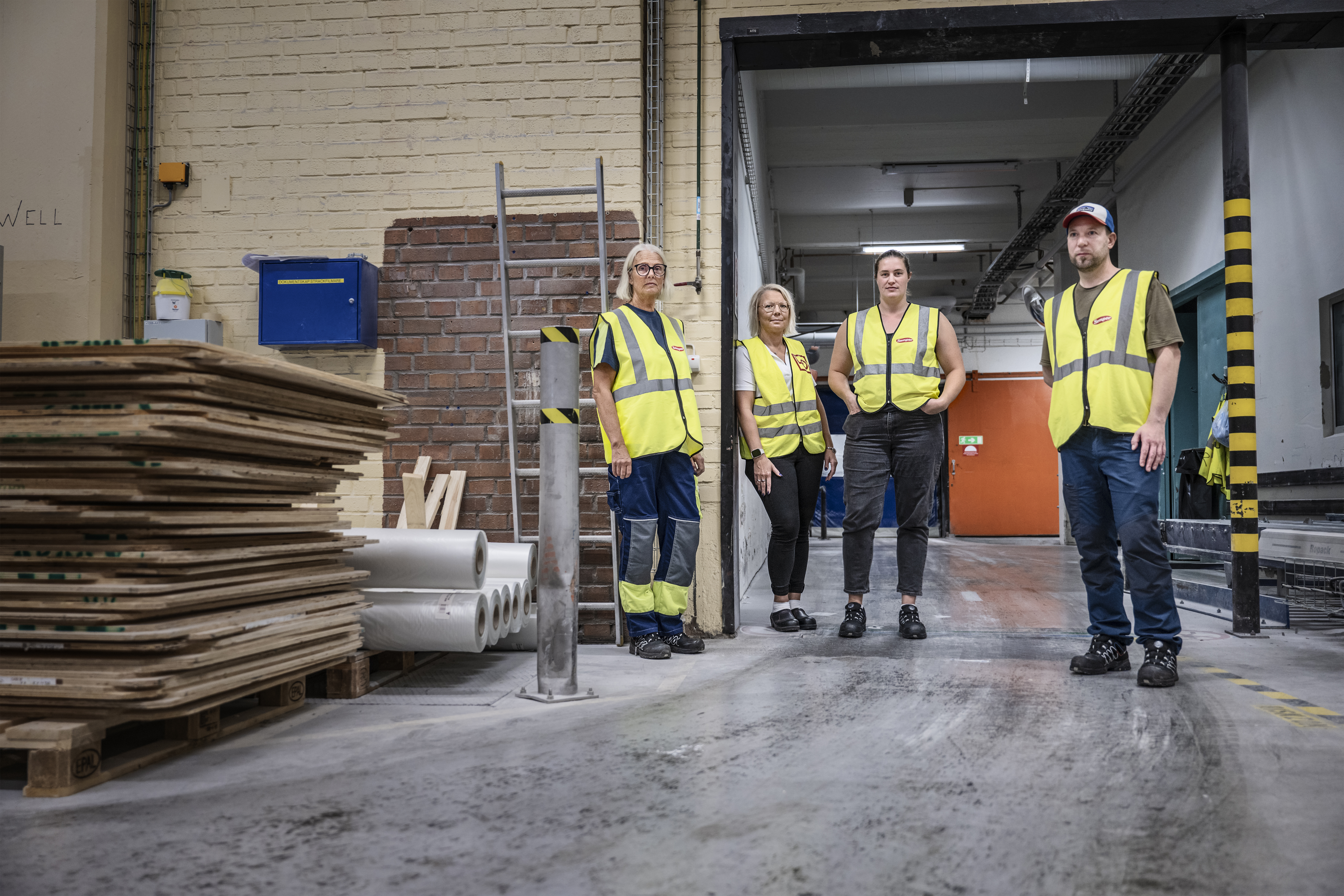 Anette Landh Jonsson, Anna Widell, Ronja Feltsten och Daniel Johansson står bredvid staplade pallar och rör i en lagerlokal.