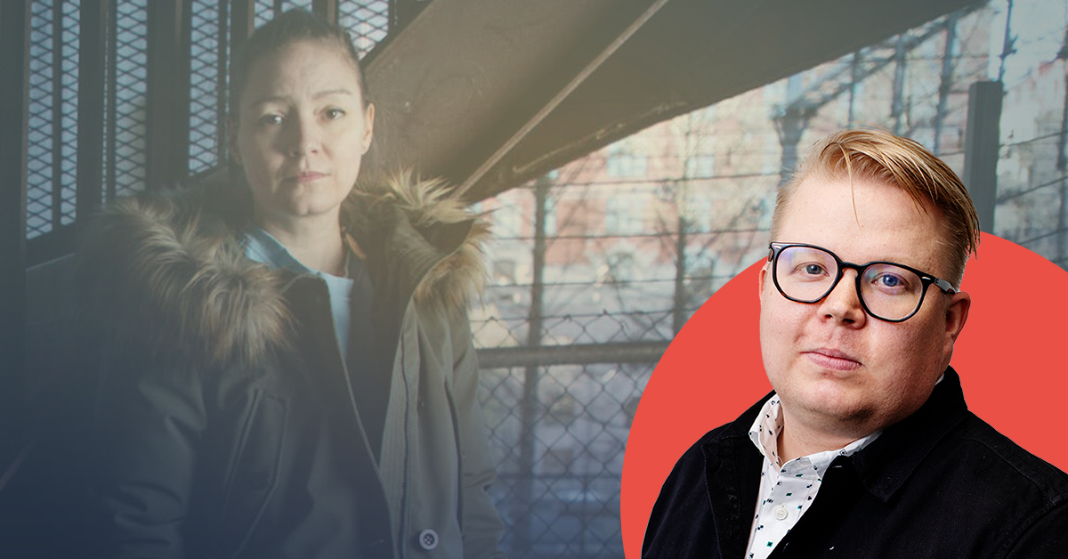 En kvinna i en kappa står framför ett staket.