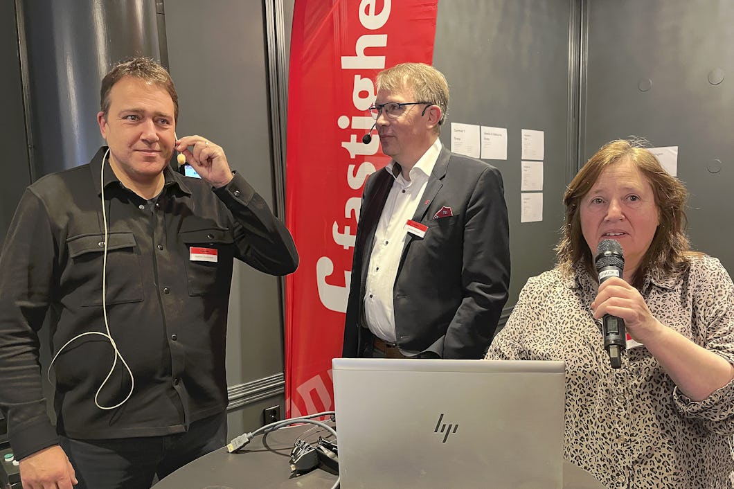 Joakim Oscarsson, Nicklas Nilsson och Ewa Edström står vid en dator med en flagga från Fastighets i bakgrunden.