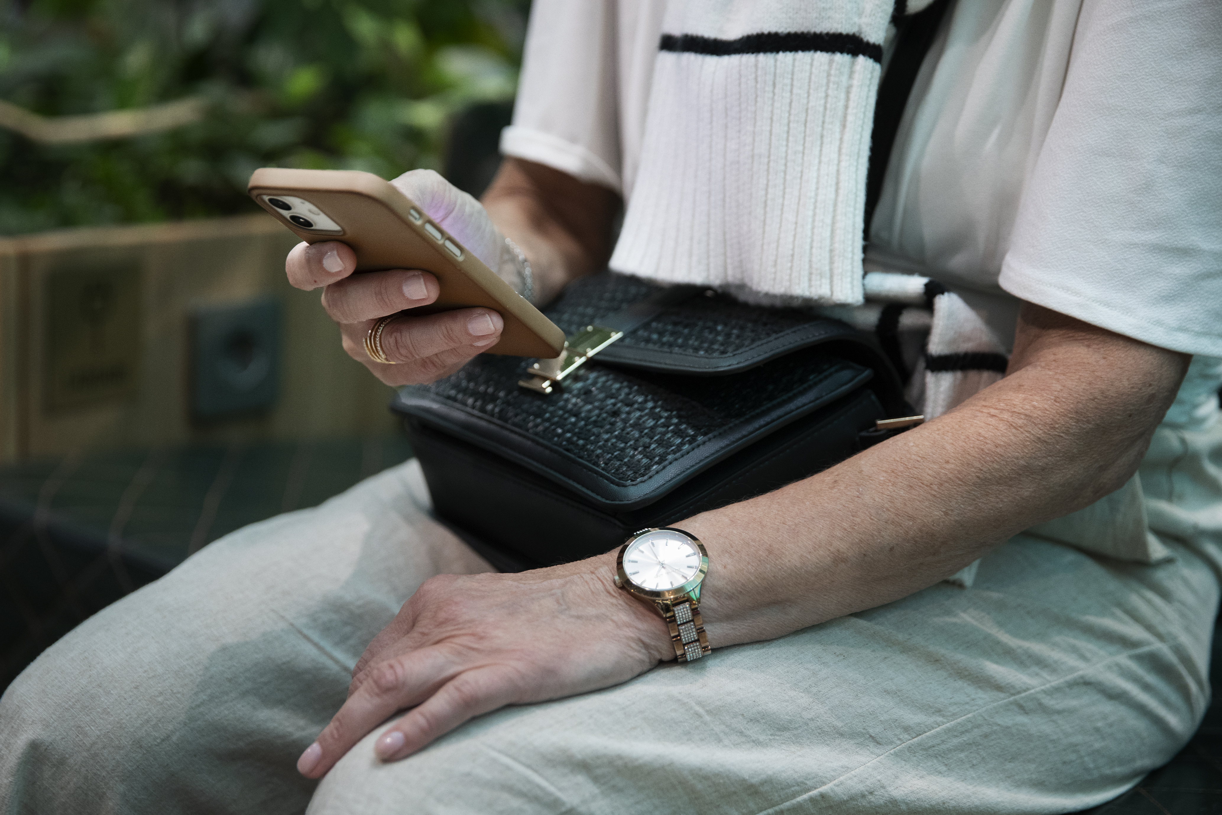 En person i vit överdel och klocka håller en smartphone.