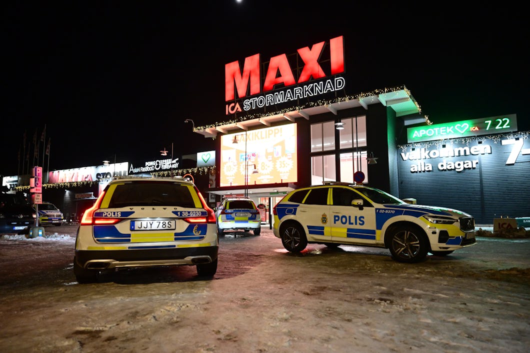 Polisbilar är parkerade utanför ICA Maxi på en snöig markyta under natten.