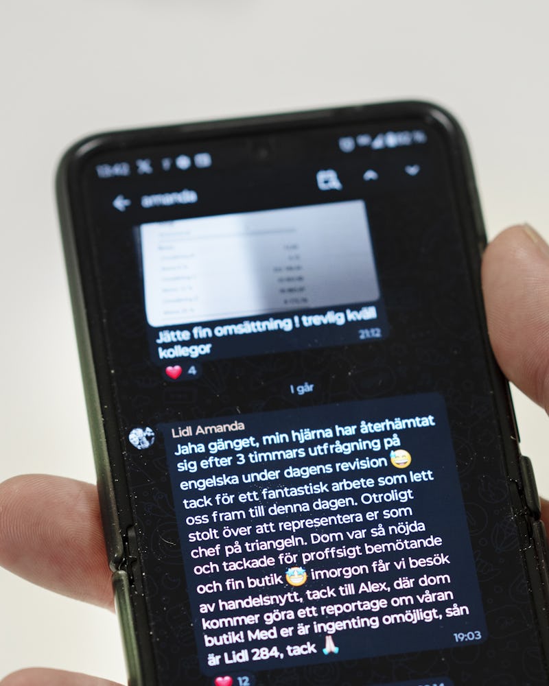 Närbild av en smartphone-skärm som visar en chattkonversation på svenska om försäljningsprestanda, med en hand som håller telefonen.