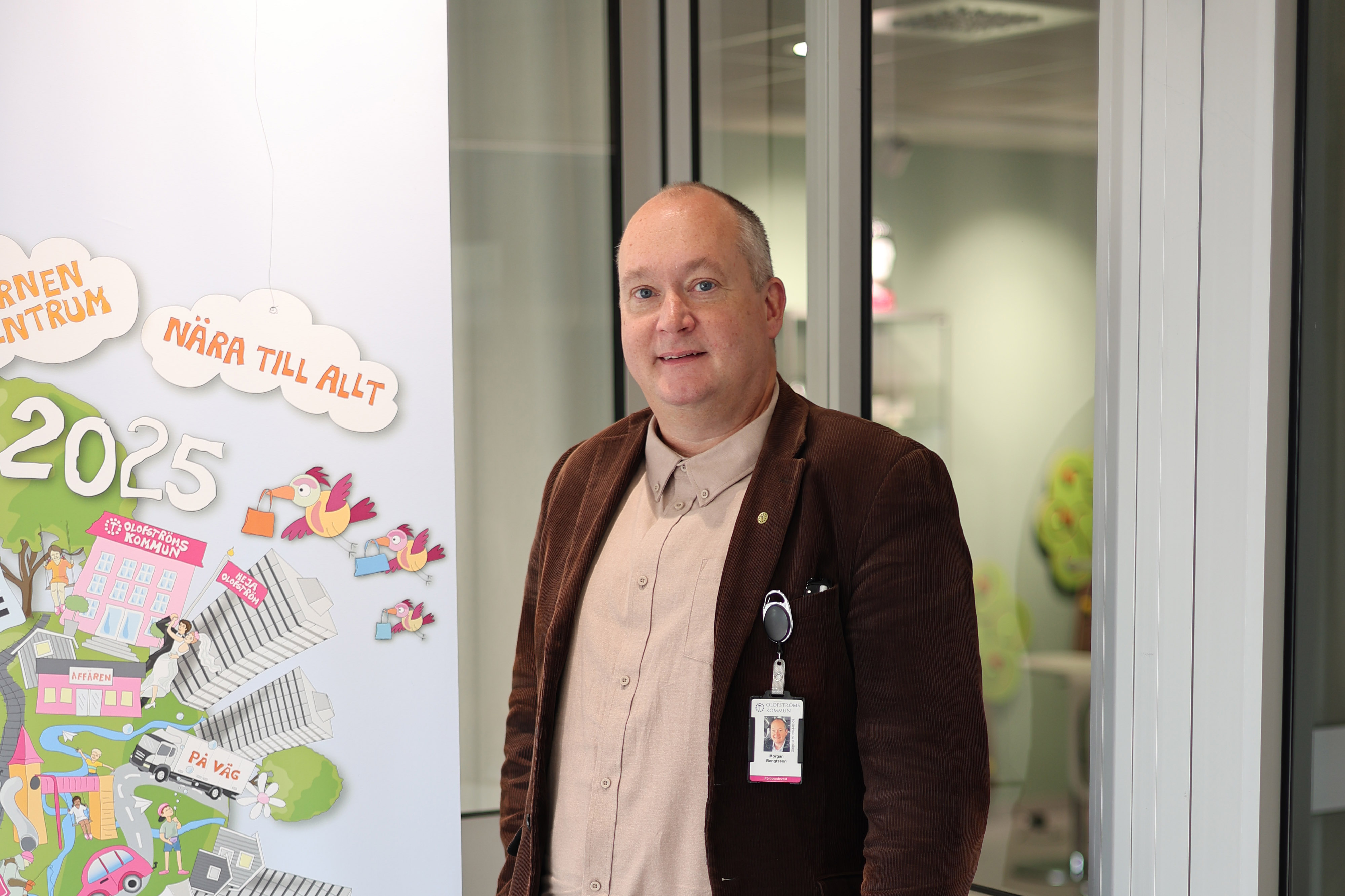 En person står inomhus bredvid en illustration på väggen med temat 2025.