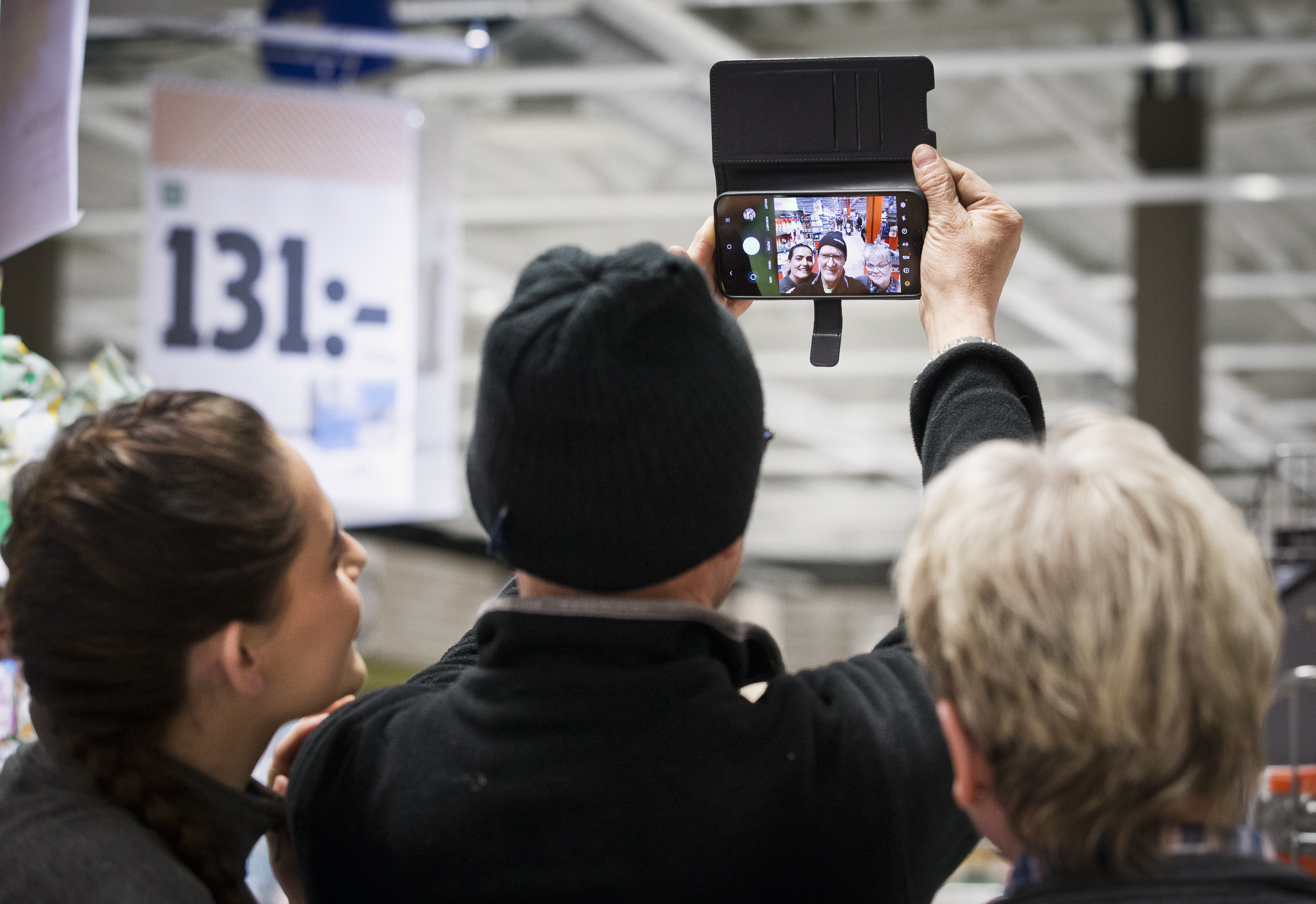 Tre personer tar en selfie i en butik.