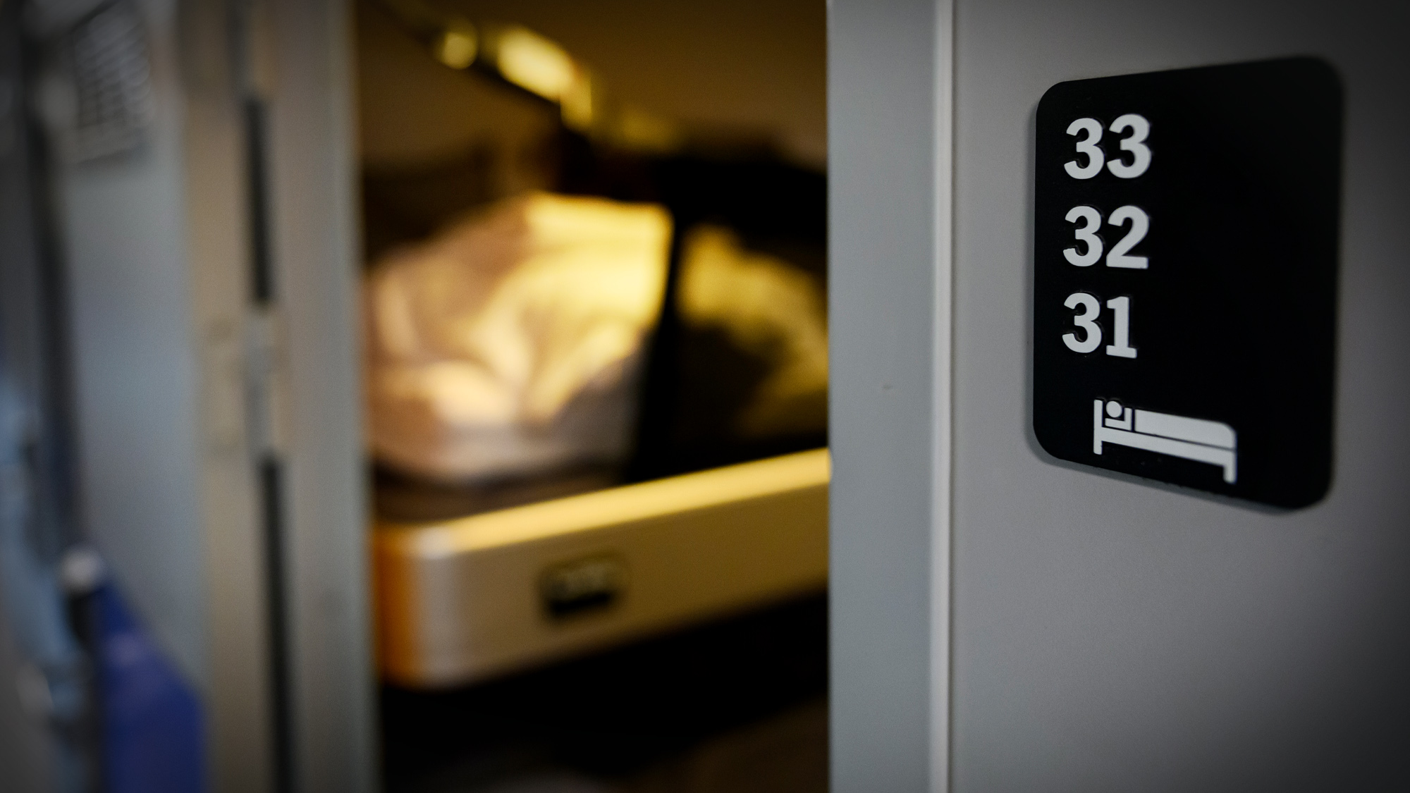 Tågkupé med sovplats i ett öppet område. Siffrorna 33, 32 och 31 syns på den grå väggen.